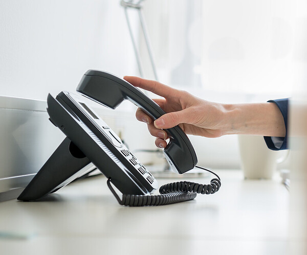 Person nimmt Telefonhörer ab