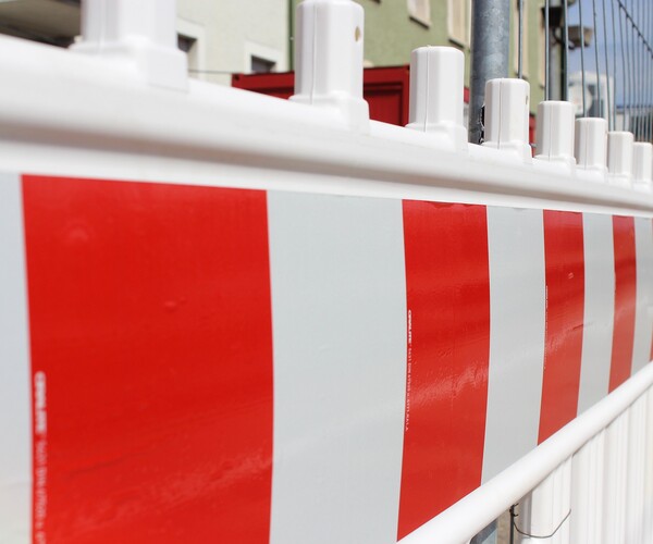 Straßenabsperrung steht neben Zaun