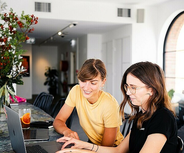 zwei Frauen unterhalten sich und schauen auf einen Laptop