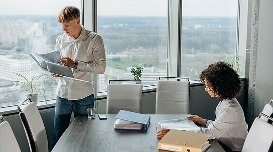 Mann und Frau in einem Büro mit Aussicht auf Stadt