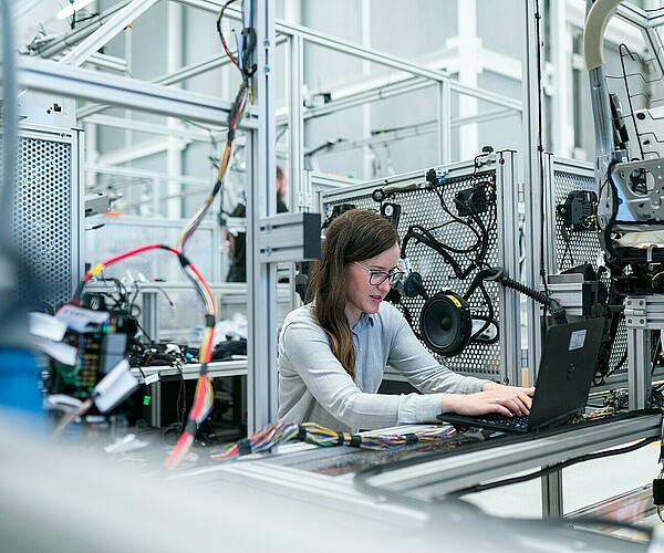 Frau arbeitet in einer Fabrik an ihrem Laptop