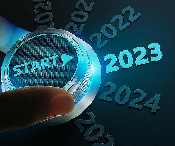 Person dreht einen Startknopf in Richtung 2023
