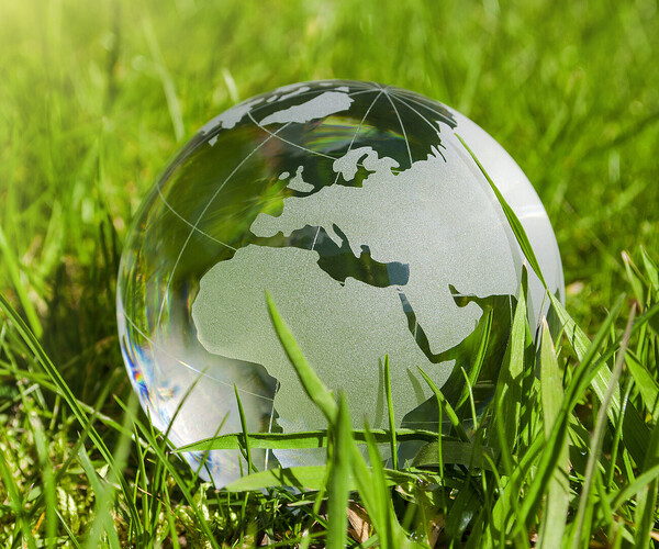 Weltkugel aus Glas, Erde mit Gras und Sonne, Naturschutz, Umweltschutz, Klimaschutz Glaserdkugel liegt auf der Erde