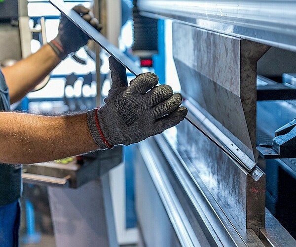 Arbeiter bearbeitet ein Stück Metall mit einer Maschine