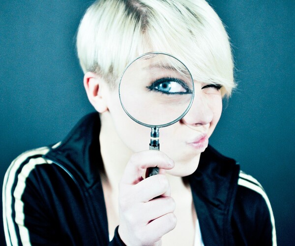 Frau hält Lupe vor ihrem Gesicht