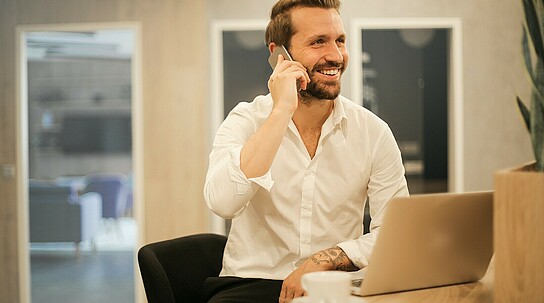 junger Mann telefoniert mit einem Lächeln