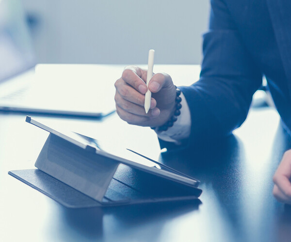 Two young business man sitting at table. man holding stylus pen with digital tablet screen. close up zwei Personen unterhalten sich und einer will etwas auf dem Tablet schreiben