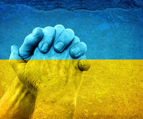 Hände in Form eines Gebets auf einer schmutzigen Ukraine-Flagge