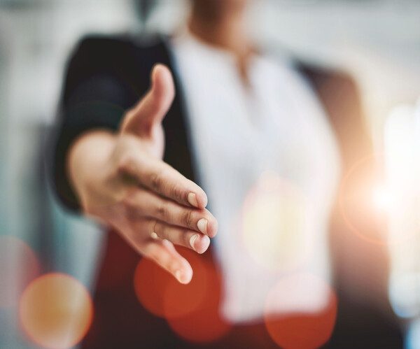 Frau im Anzug reicht dem Zuschauer die Hand
