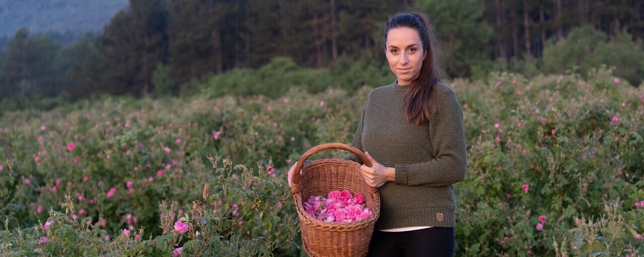 Diana Deltschew steht zwischen den Rosen mit einem Erntekorb
