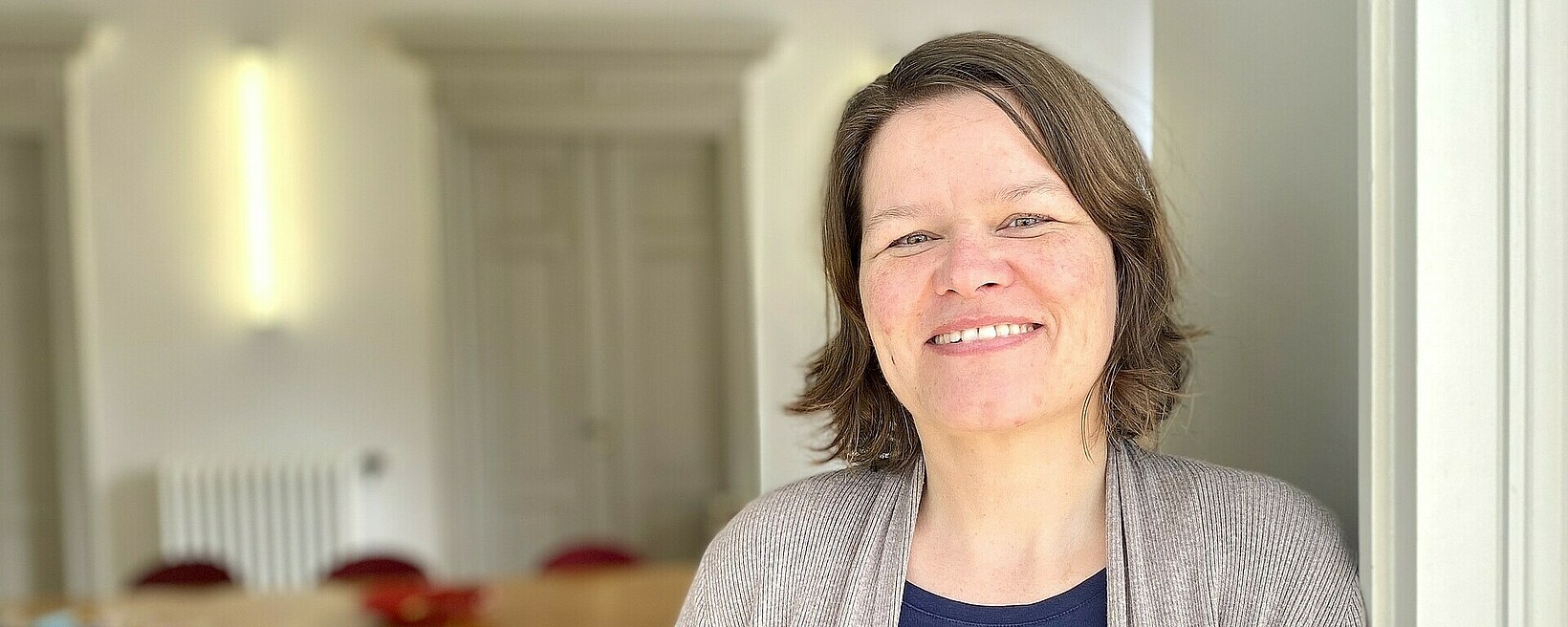Jenny Roleder Jenny Roleder von ZAROF. lehnt an einem Türrahmen, im Hintergrund ein Tisch mit Stühlen